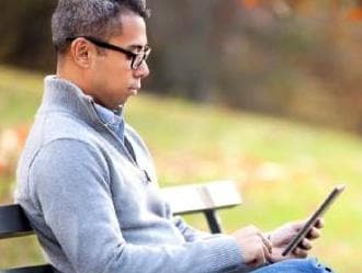 Man sitting on bench and looking at tablet