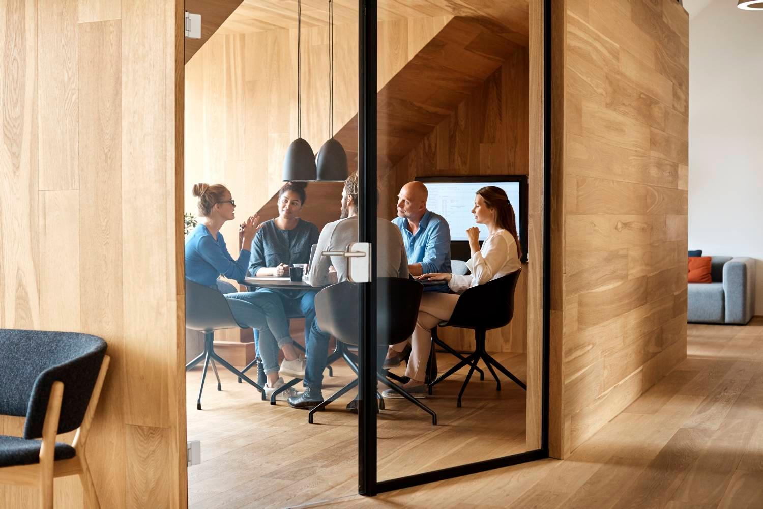 Business professionals discussing in meeting seen through glass door at office