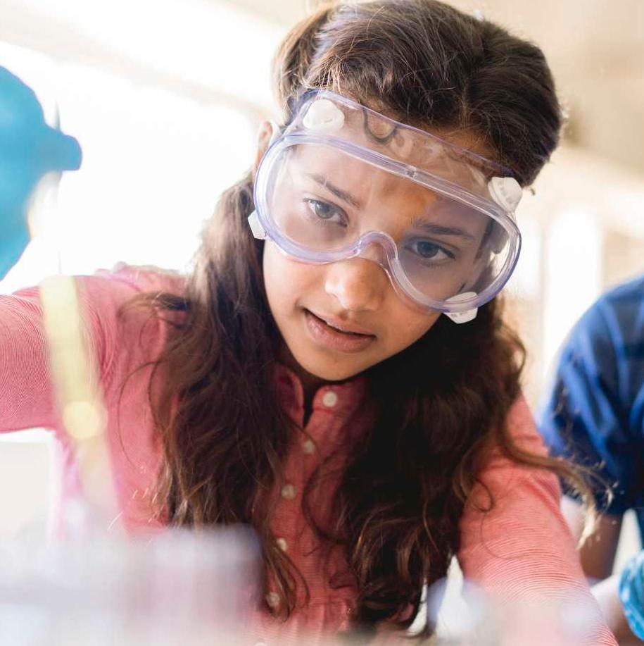 Young girl student in science lab with safety goggles on