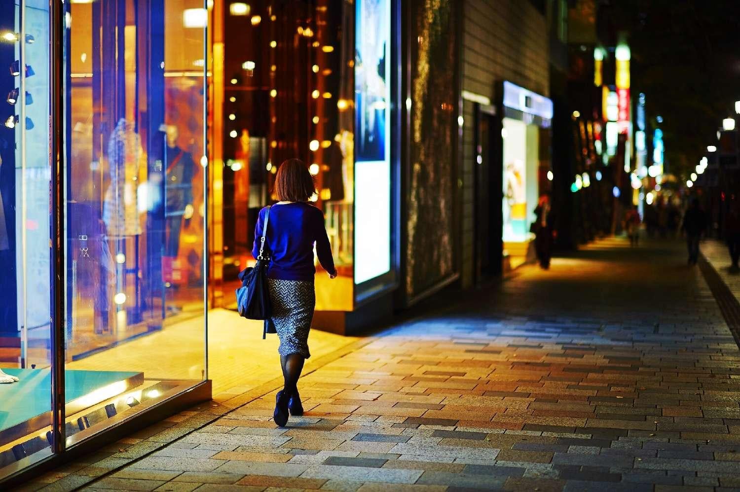 Female shopper walks past stores at night