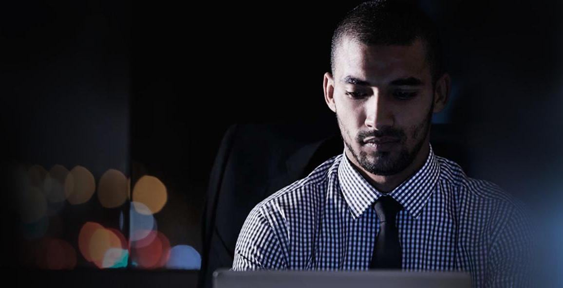 Man with tie on laptop at night