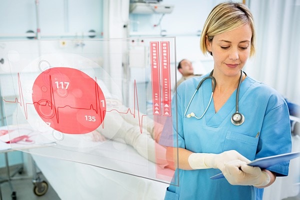 Nurse using a tablet in a hospital room with a data visualization display in front of her
