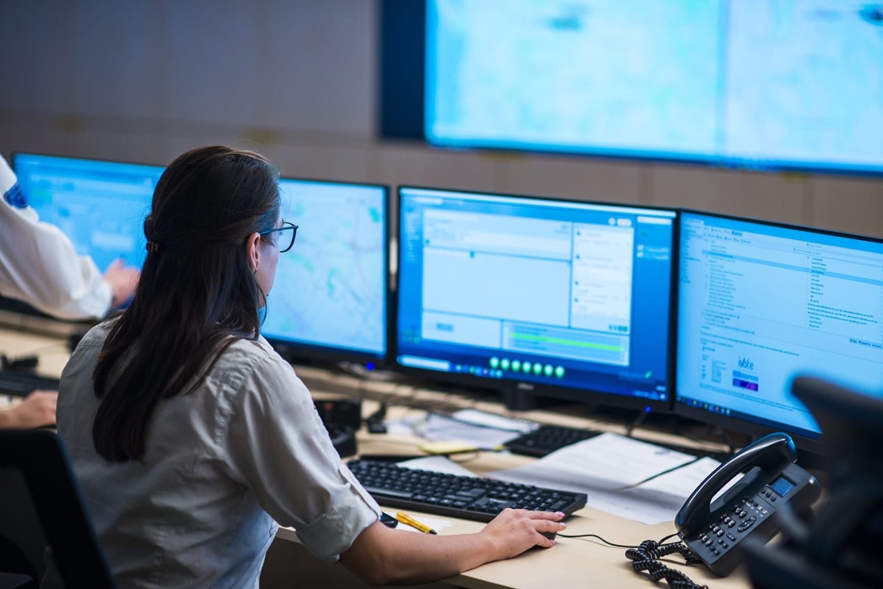 Female police officer using multiple monitors