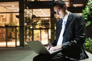 Man Working On Laptop Sitting Outside Office Building