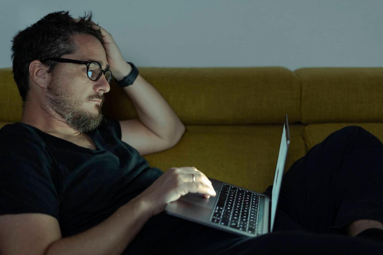 Man working on laptop late at night on couch