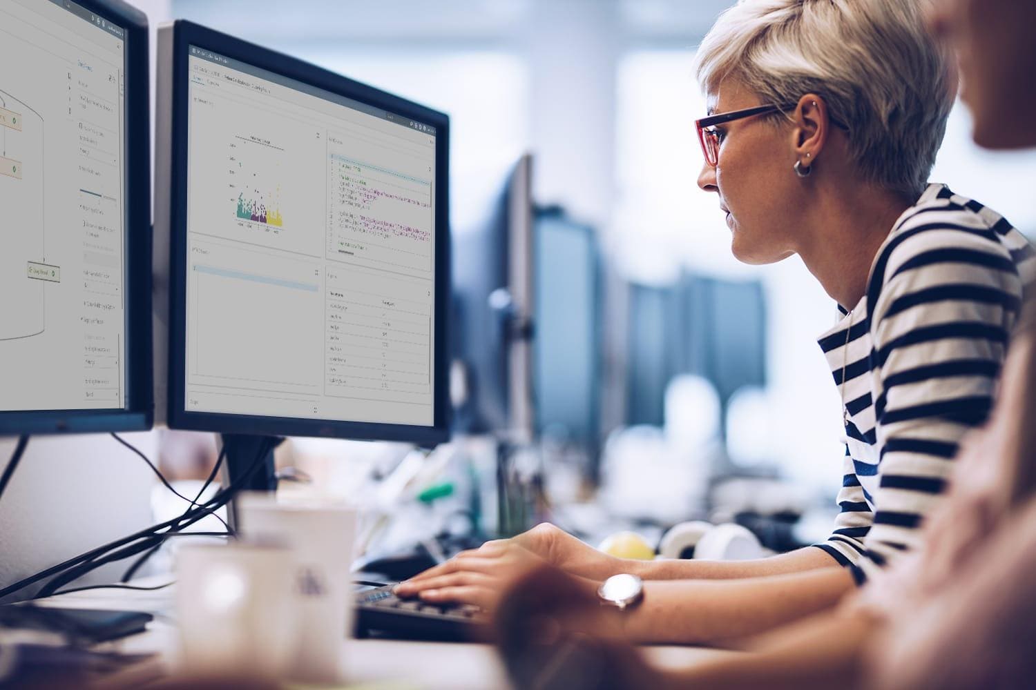 Female data scientist coding with desktop computers