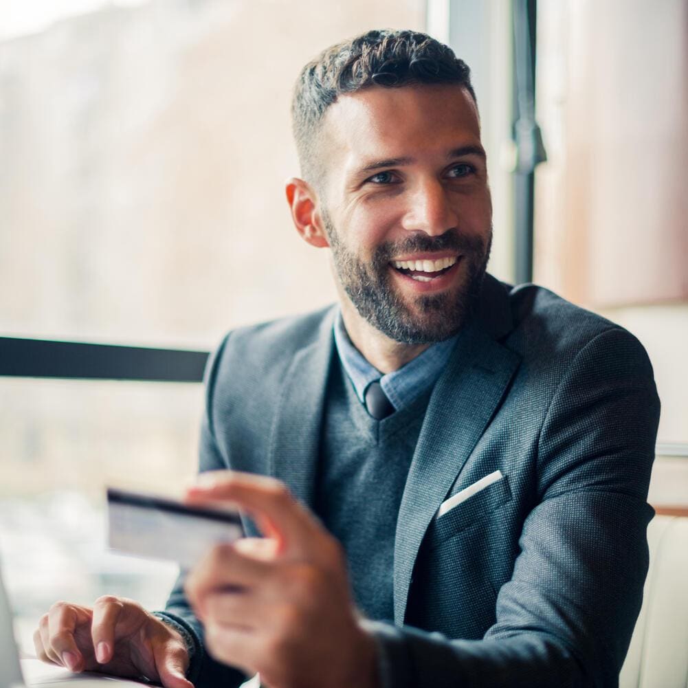 Businessman sitting holding a credit card near a window