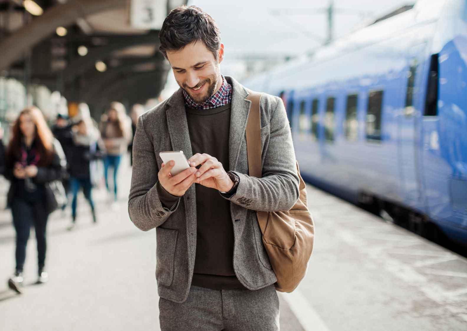 Businessman using mobile phone at train station