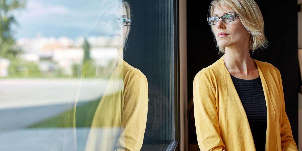 Femme cadre tenant une tablette et regardant par la fenêtre