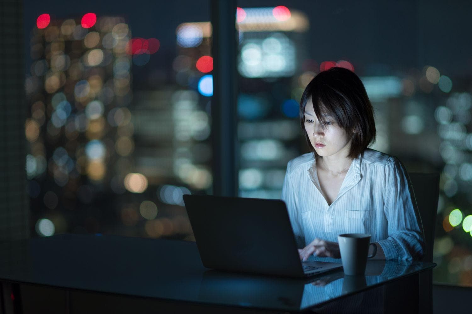 Woman working with laptop at night in office