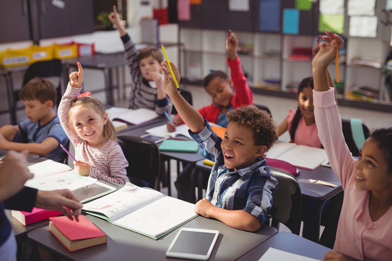 Children raise hands in classroom