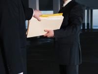 two business men exchanging files - possibly for fraud