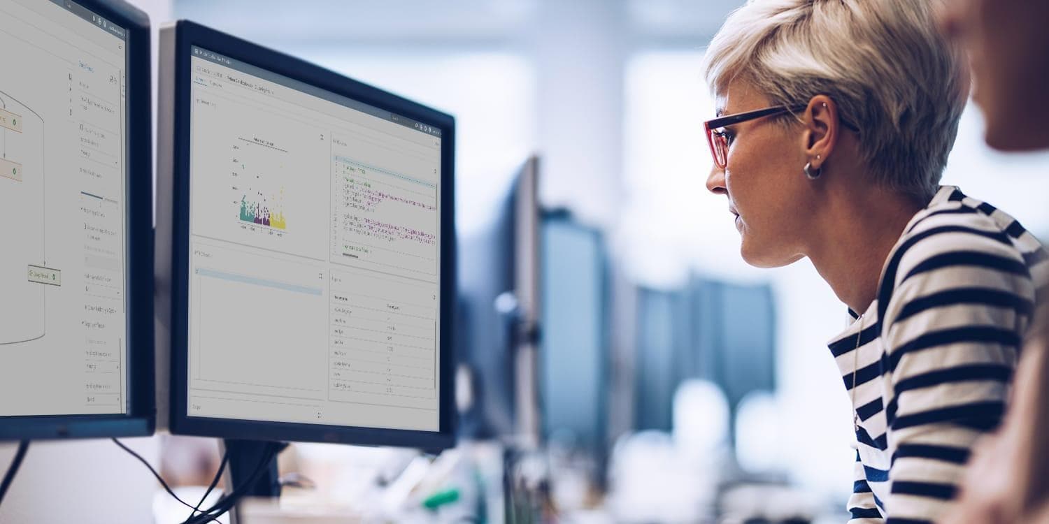 Female data scientist coding with desktop computers