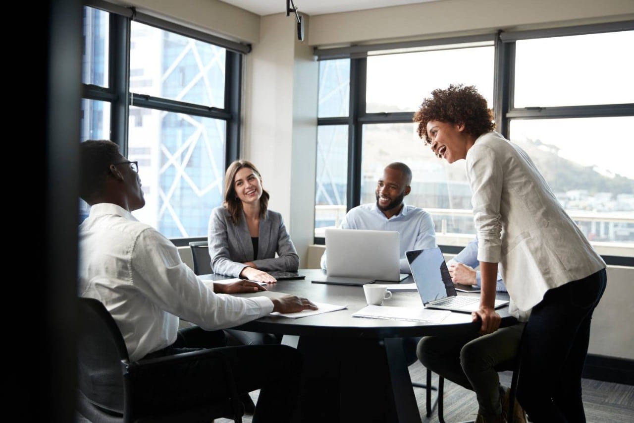 Millennial black businesswoman stands listening to corporate colleagues at a meeting, close up Millennial black businesswoman stands listening to corporate colleagues at a meeting, close up