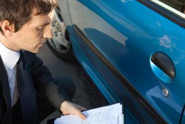 Insurance adviser examining damage to car exterior