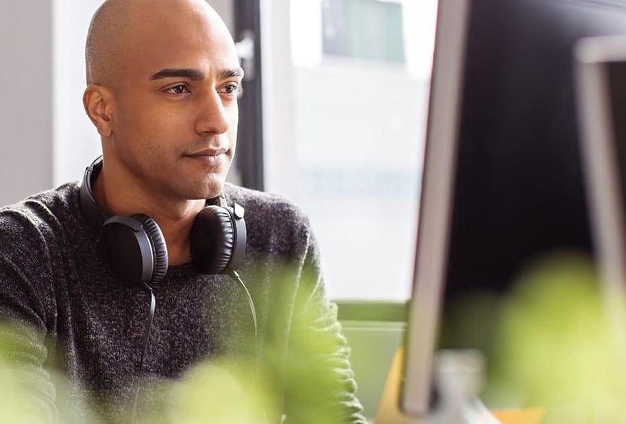 Business man with headphones working on desktop pc in office