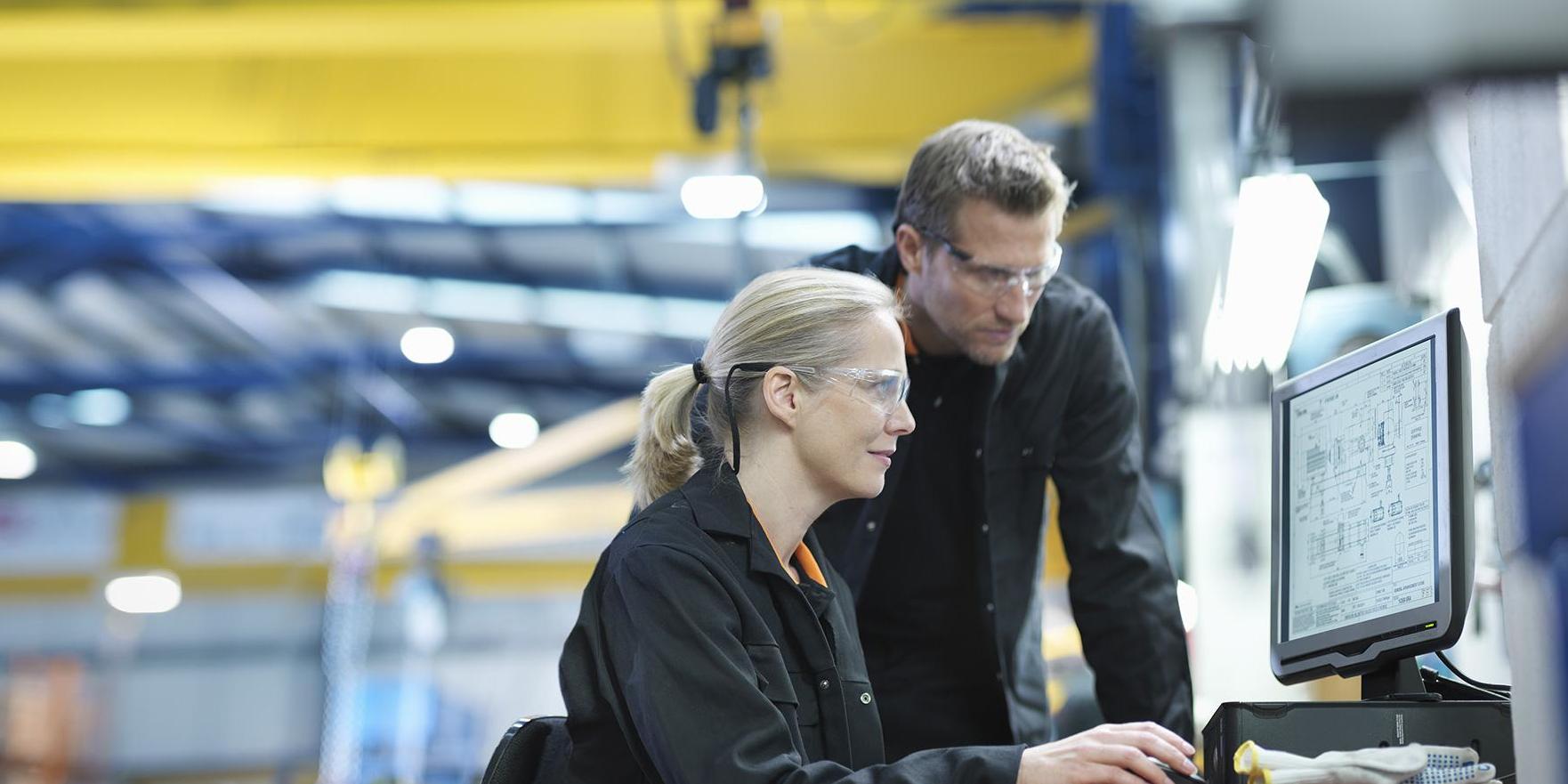 Man and woman in front of computer screen in factory