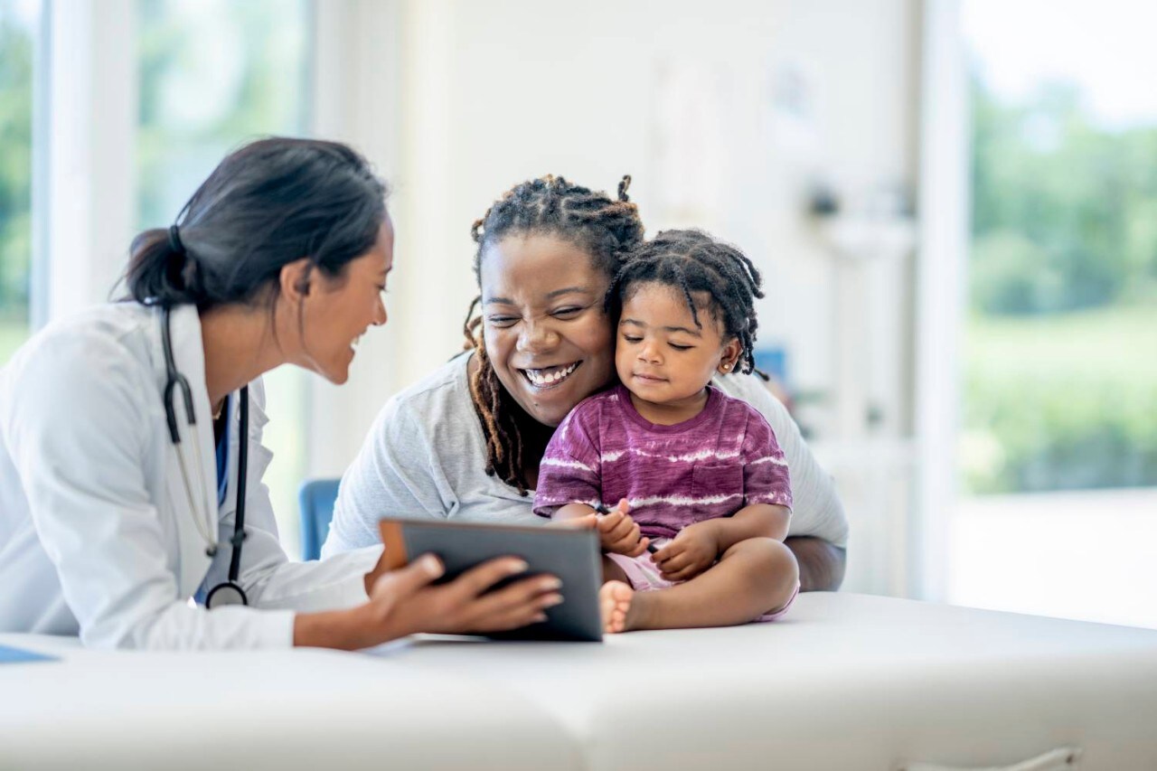 Mother and daughter smiling at tablet in doctors office