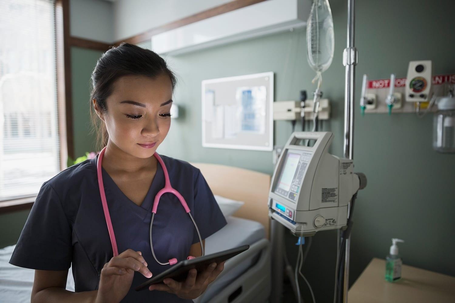 Nurse using digital tablet in hospital room