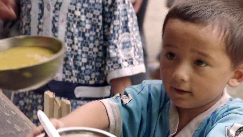 Nepalese boy receives bowl of food as part of IOM's relief efforts