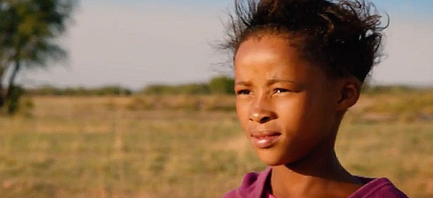 草原地帯の彼方を見つめるナミビアの少女