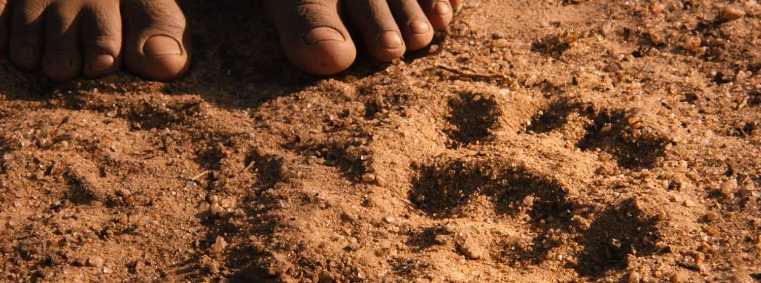 砂に残る足跡を見るナミビアの少女の足元