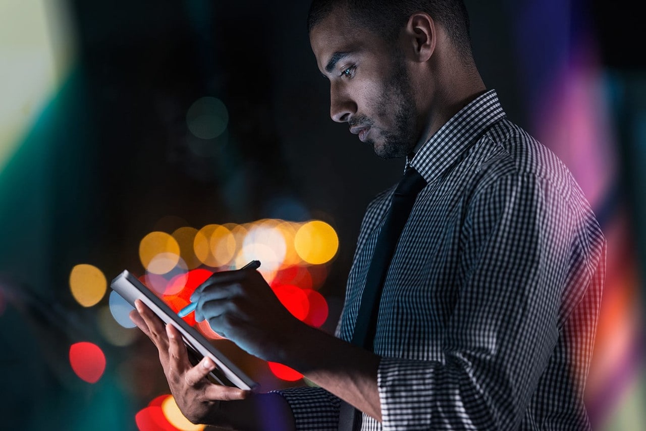 Young businessman using his tablet while working at night