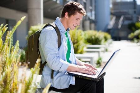 Male student using laptop outdoors