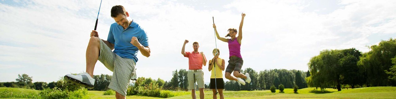  Four friends golfing together -- a man and his three friends celebrates his putt while golfing on a summer day