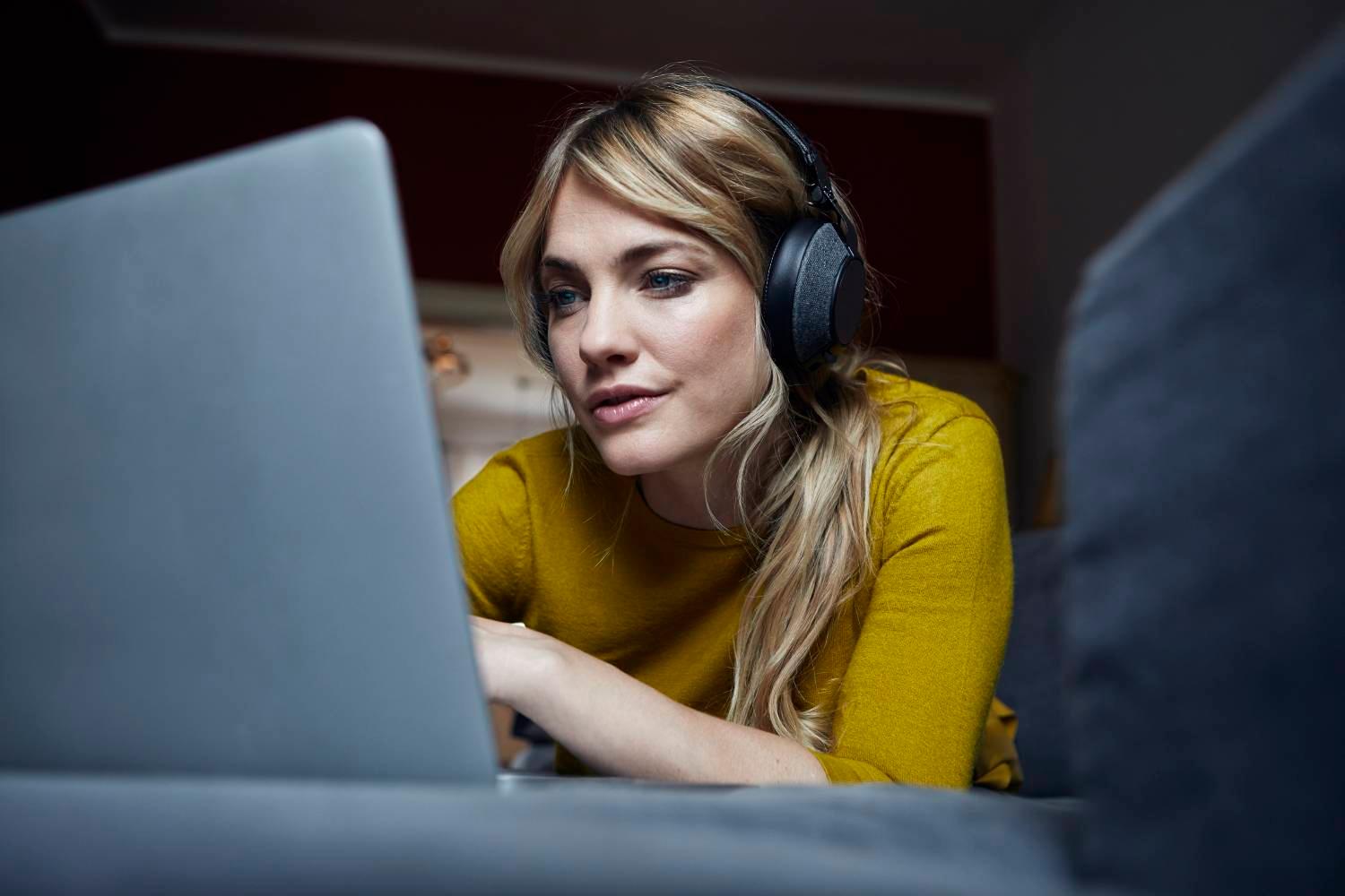 Woman working on laptop using headphones