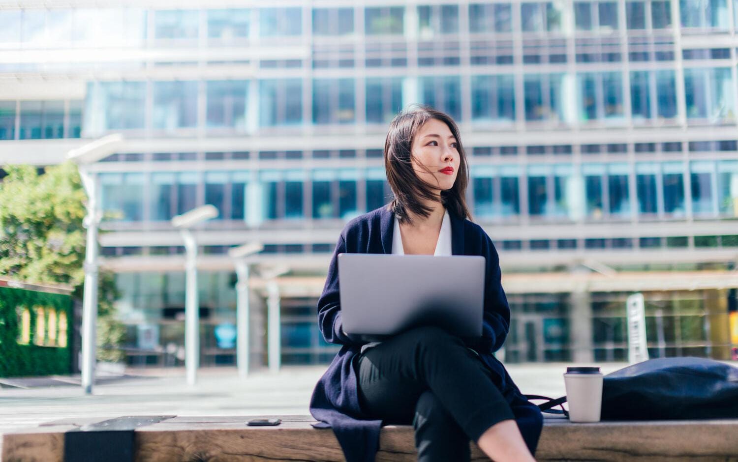 A woman working on a bench outside of an office building