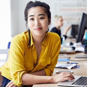 Businesswoman looking at female colleague with coworkers sitting in background