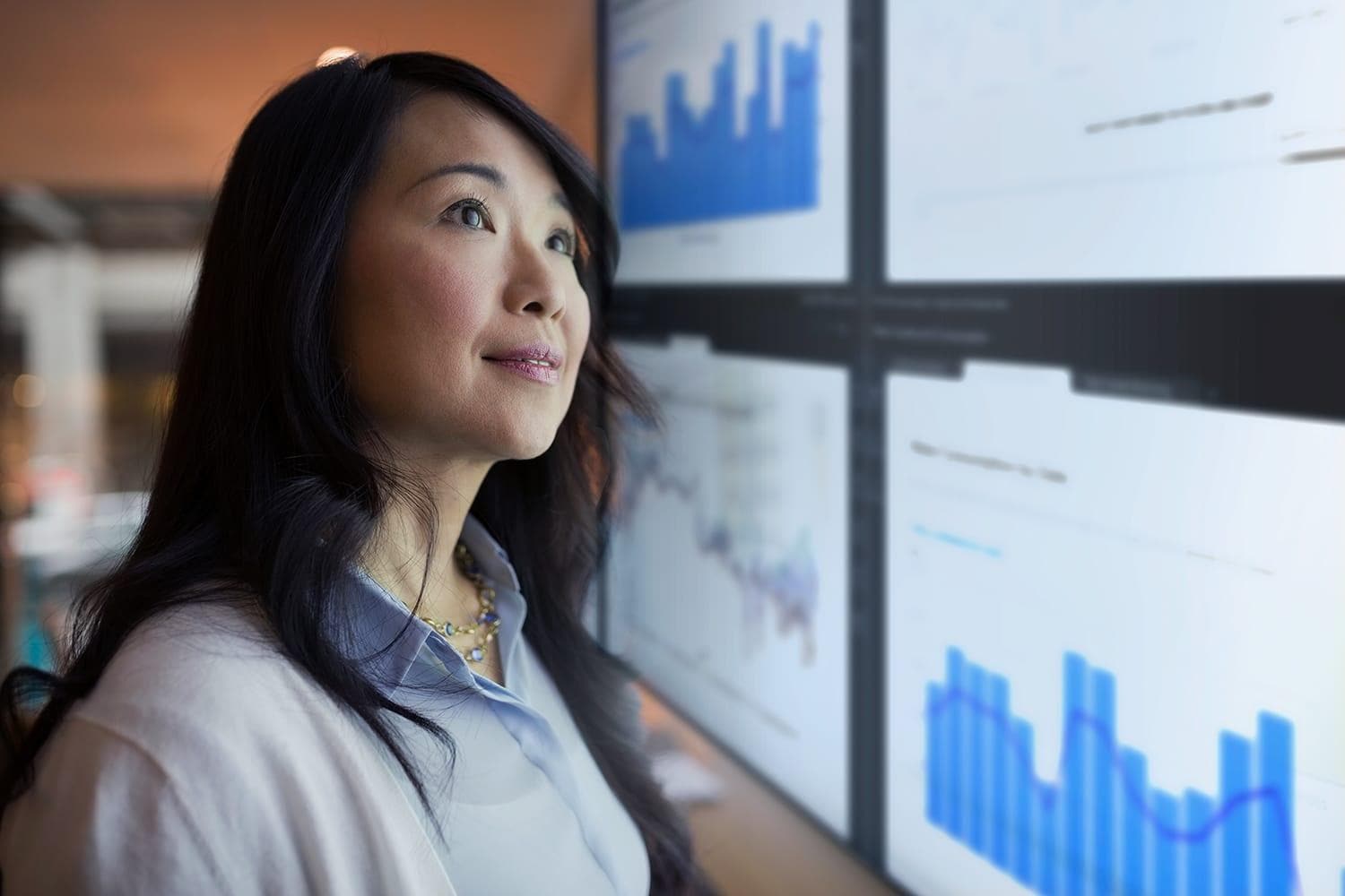 Asian woman views SAS data visualizations on large display