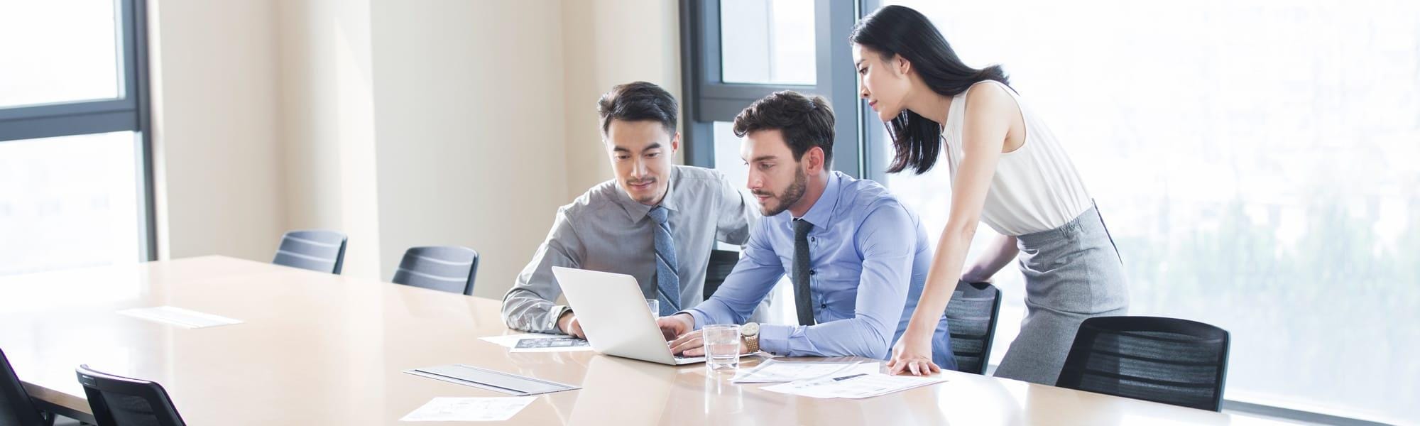 Young business colleagues studying data around a laptop in office