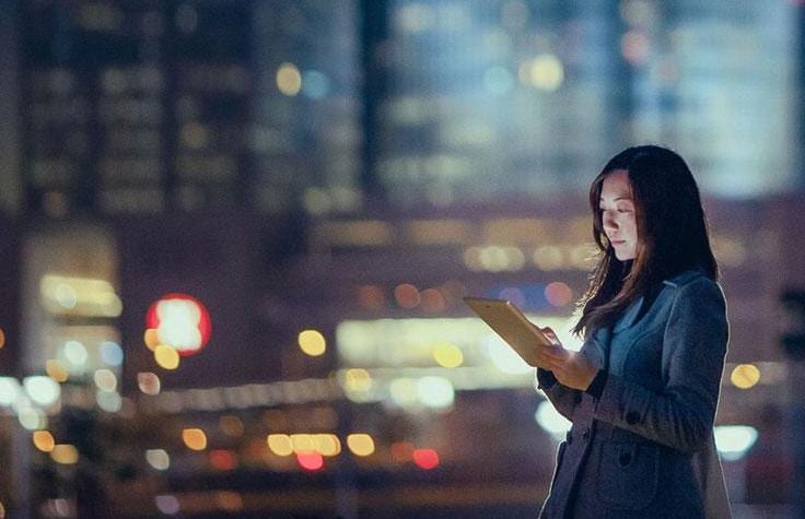 woman using tablet at dusk in the city