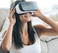 Future is now -- attractive young woman adjusting her VR headset and smiling while sitting at home  