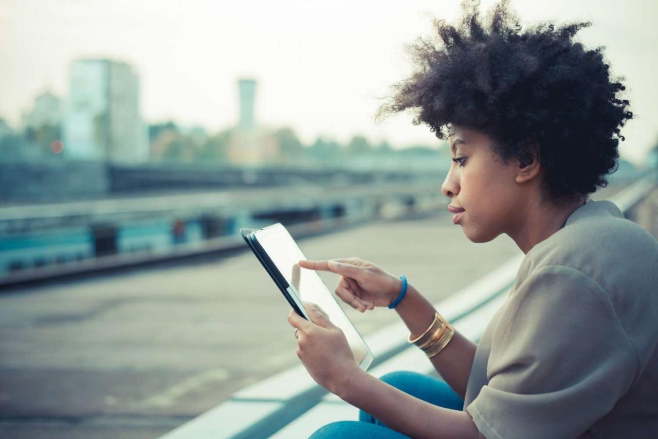 Young woman using touchscreen on digital tablet on city rooftop