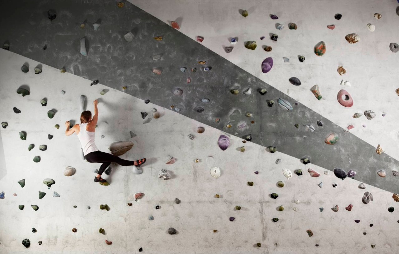 Female climber clinging to indoor climbing wall  