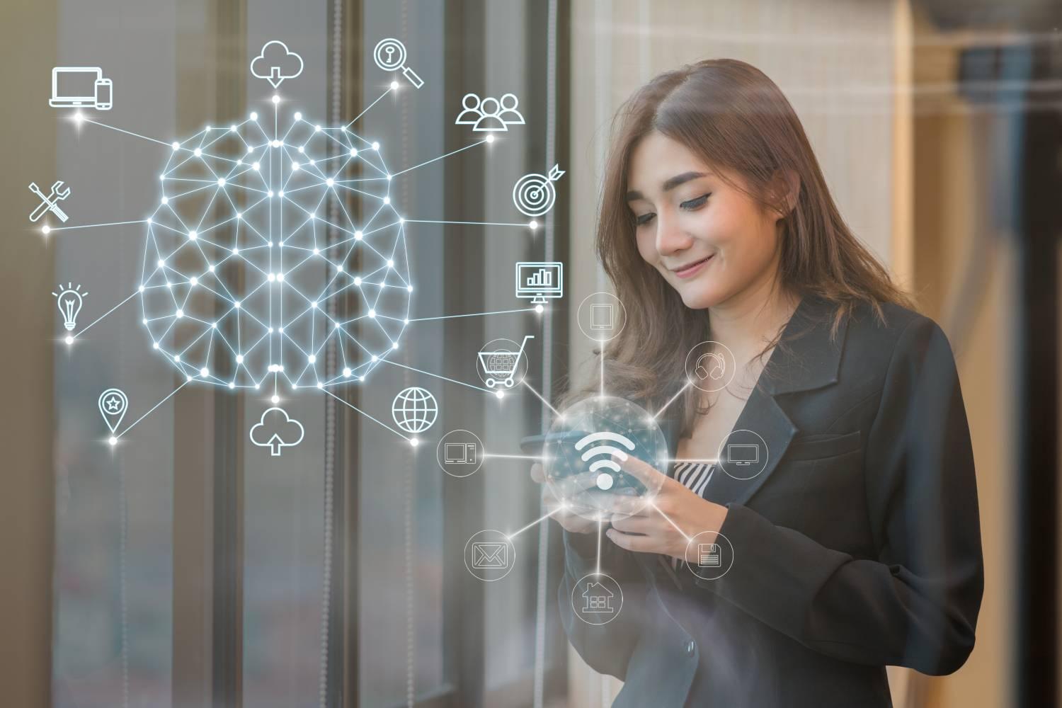 Asian Thai businesswoman using mobile smartphone to connect to AI and IoT driven omnichannel digital experiences
