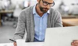 Business man with glasses at laptop computer in modern office setting