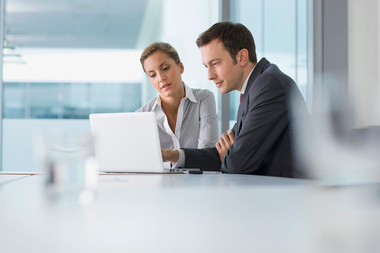 Businessman and businesswoman using laptop in office