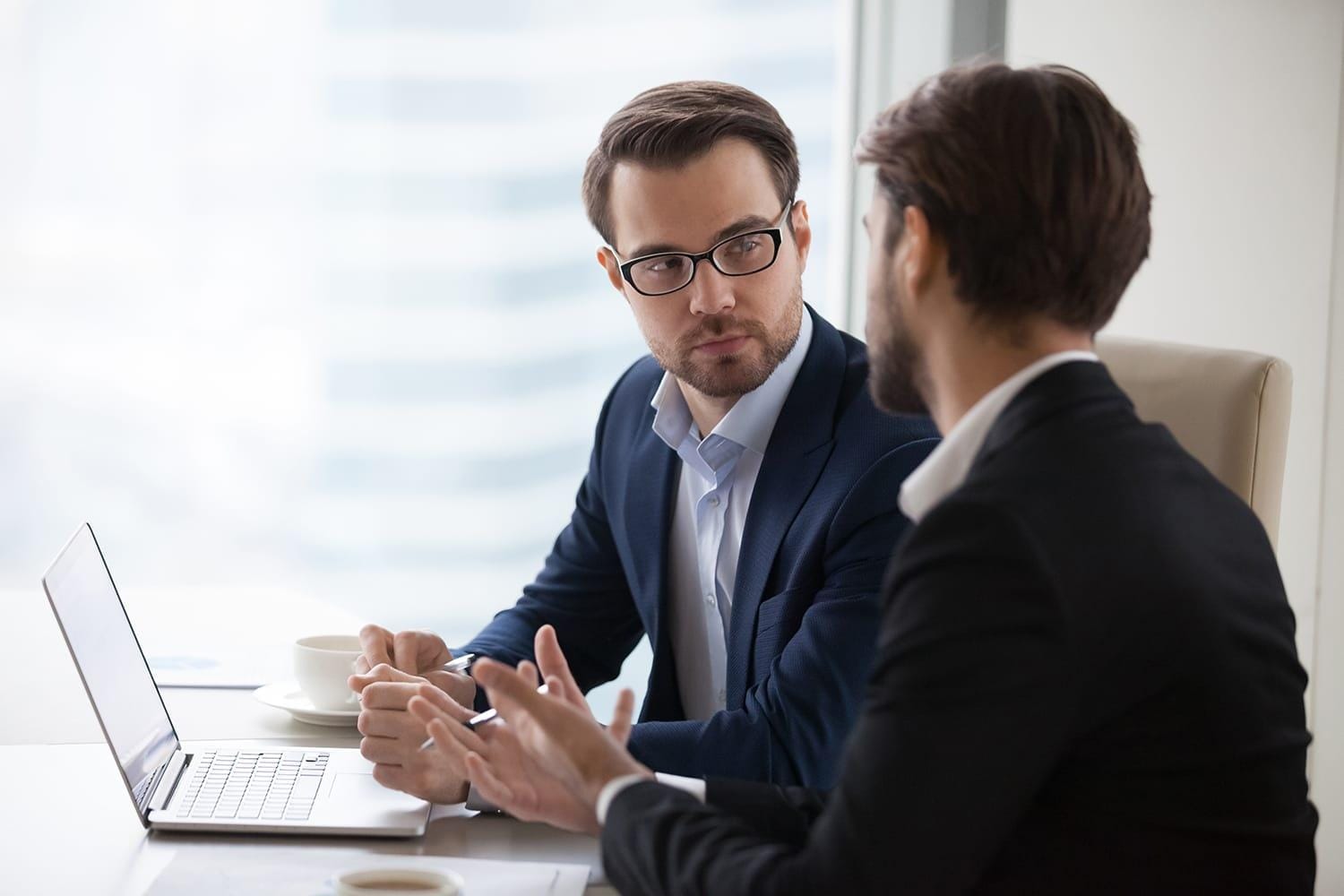 Two young businessmen discuss project in office