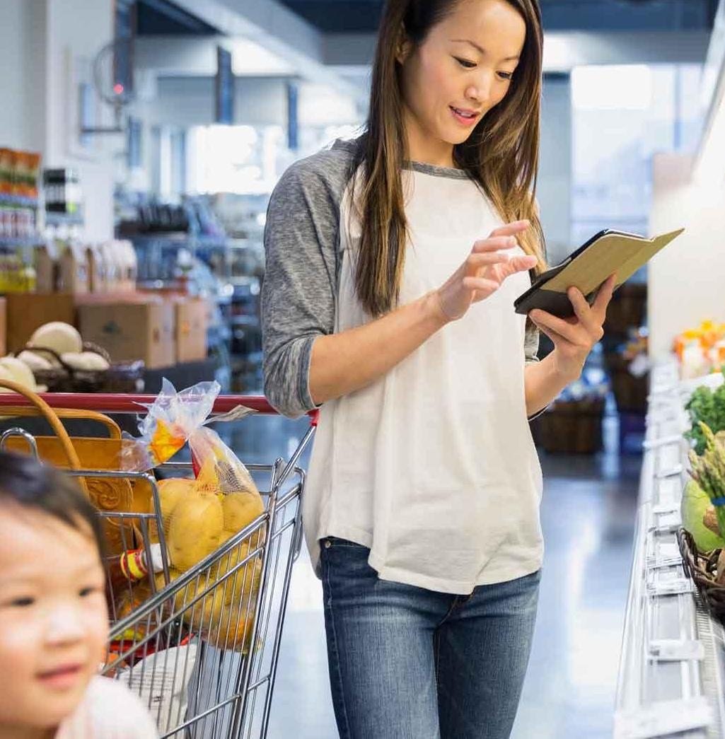 Young mom grocery shopping with list on phone