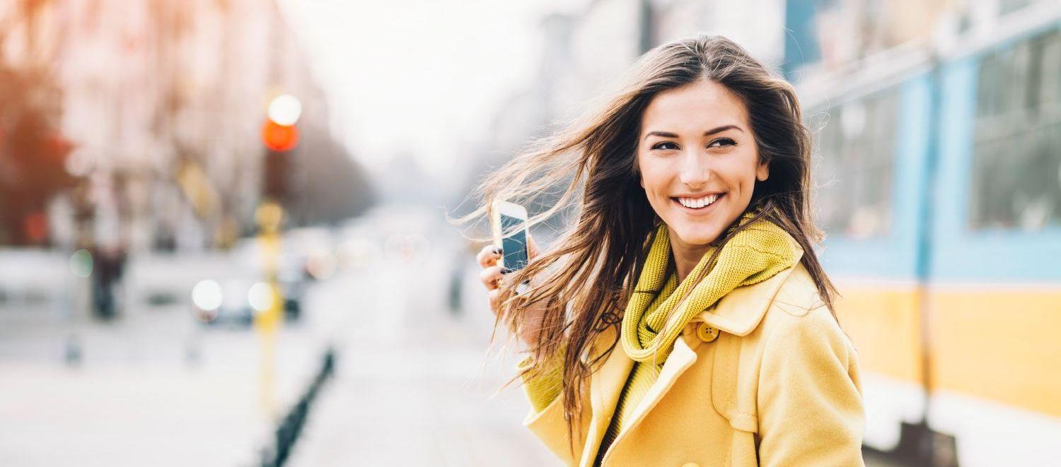 Smiling woman with a phone on street