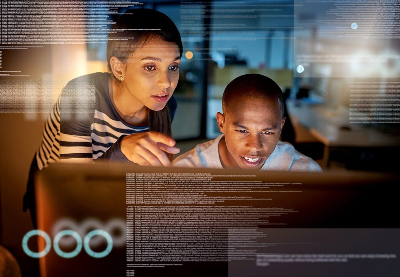 Male and female coworkers viewing data on desktop monitor