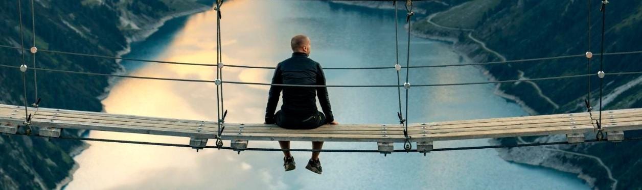 Man sitting on bridge over lake