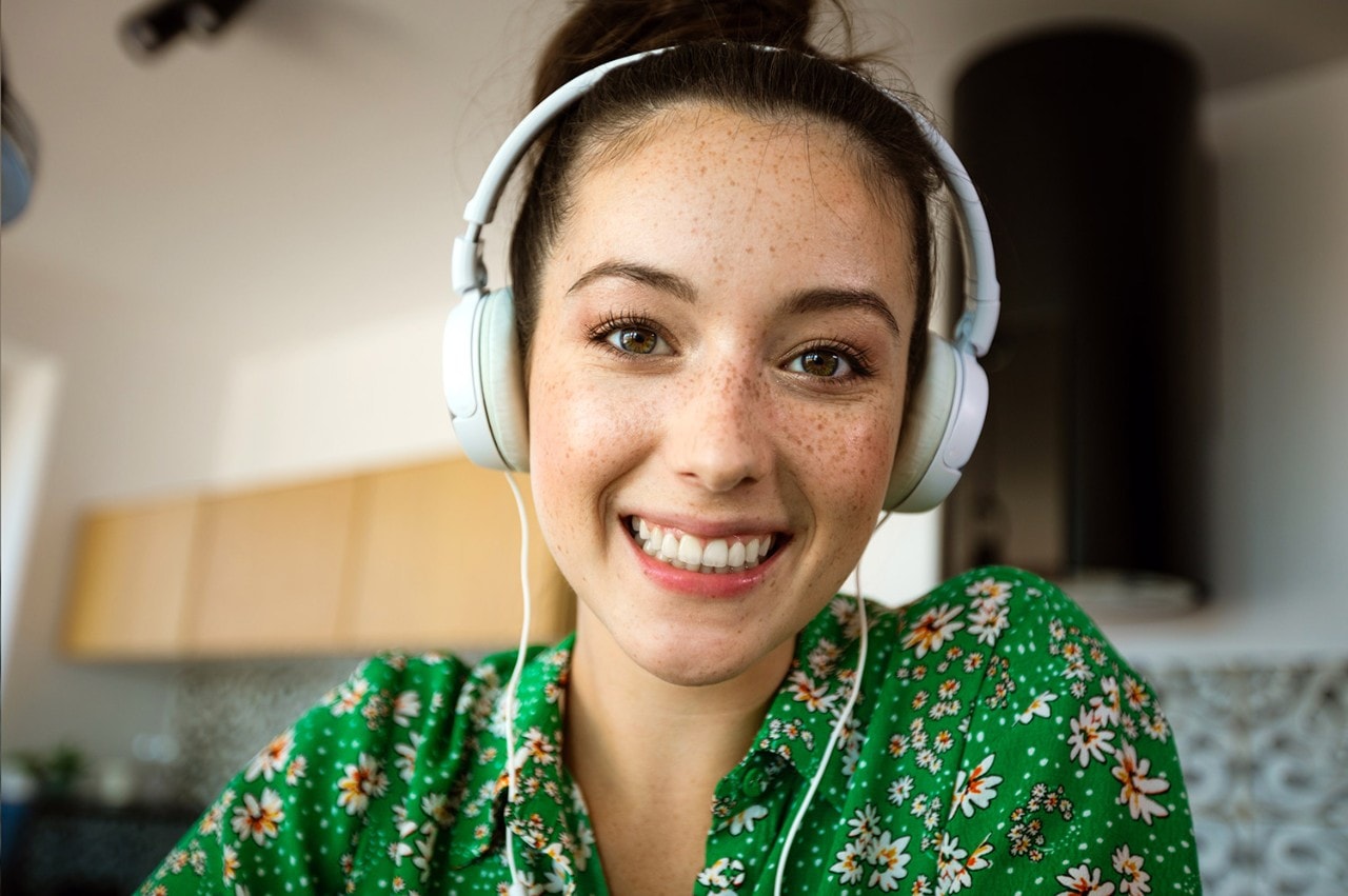 Woman smiling at camera wearing headphones in a green shirt