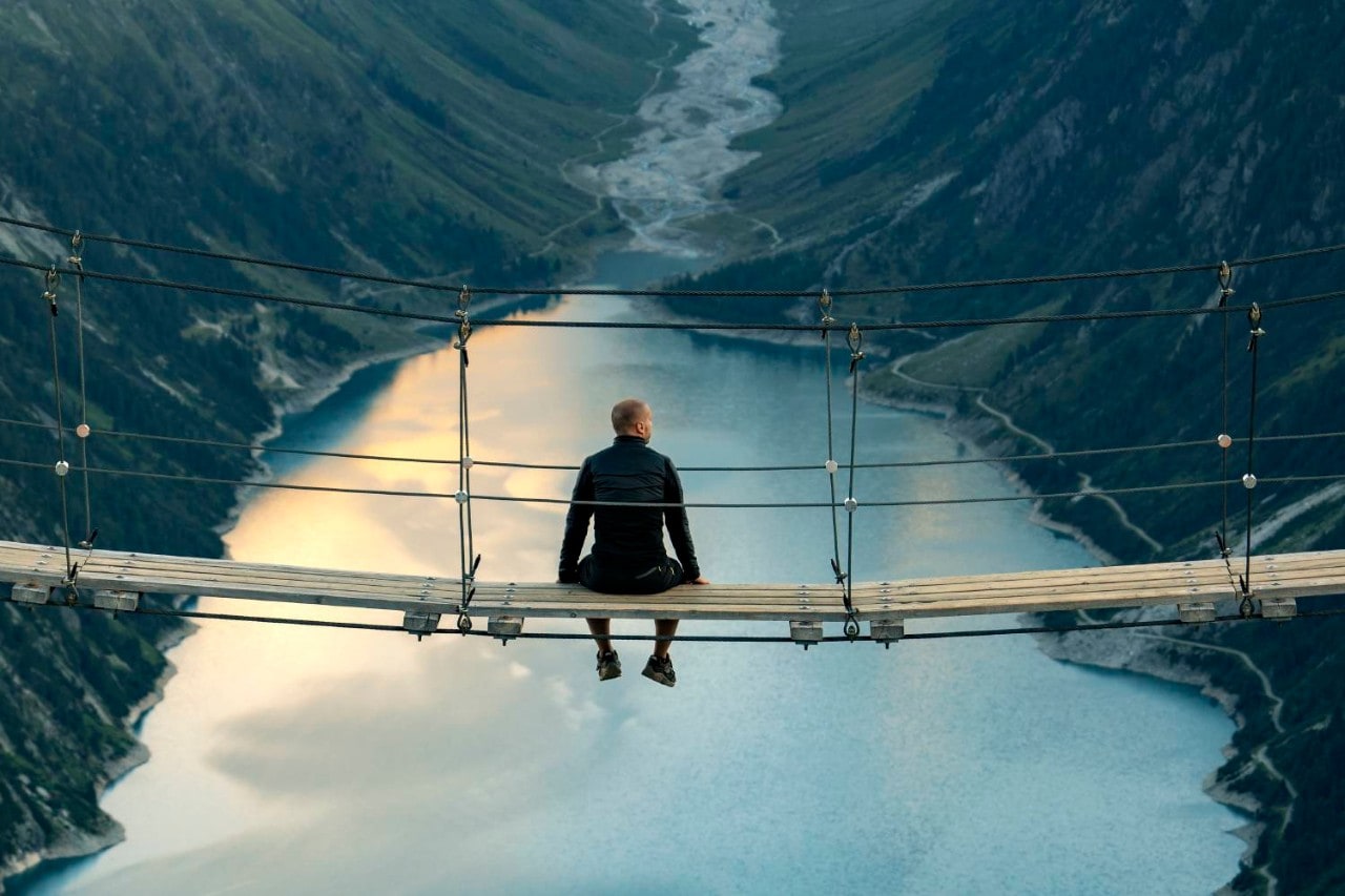 Man sitting on bridge over lake