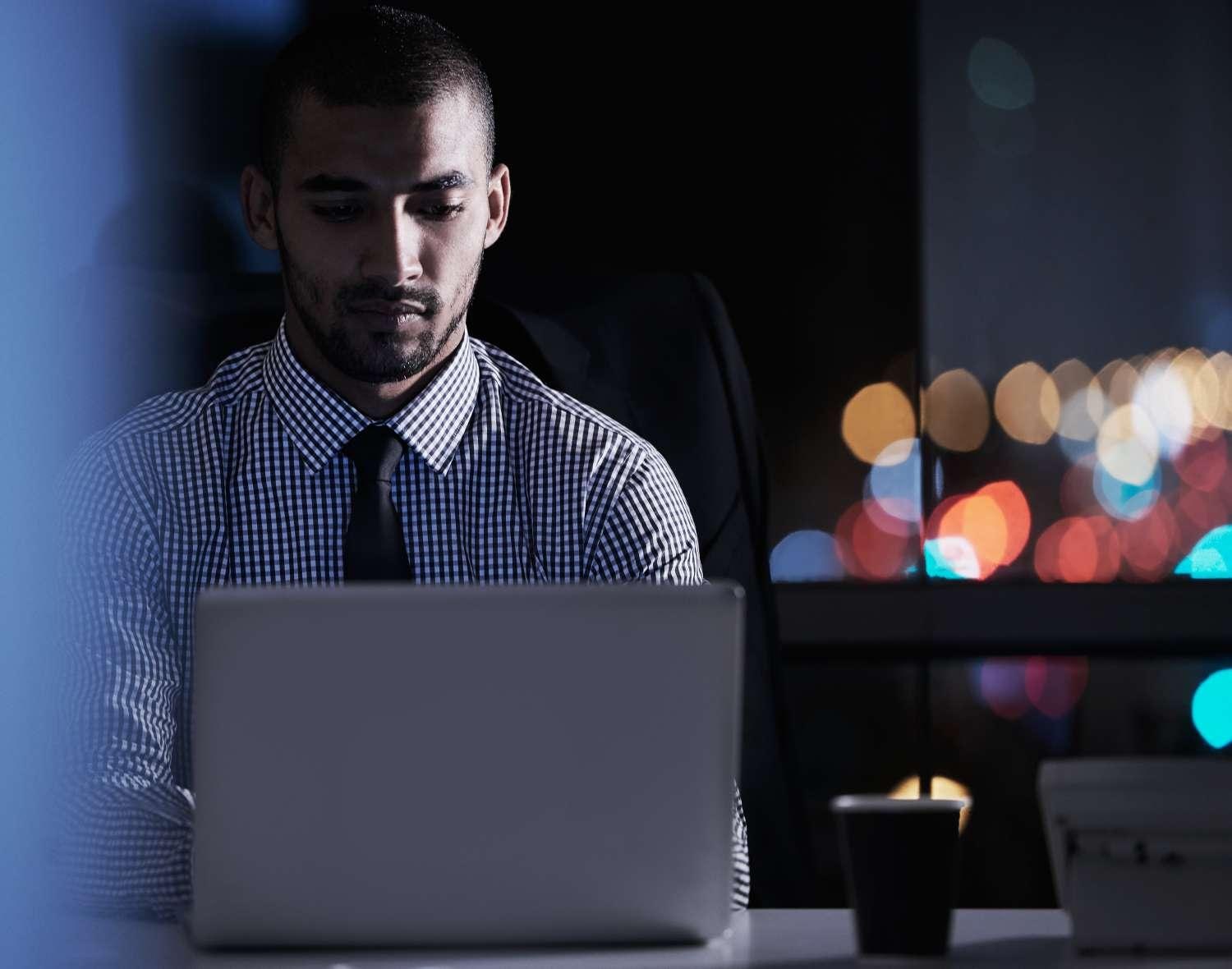 Man with tie on a laptop at night