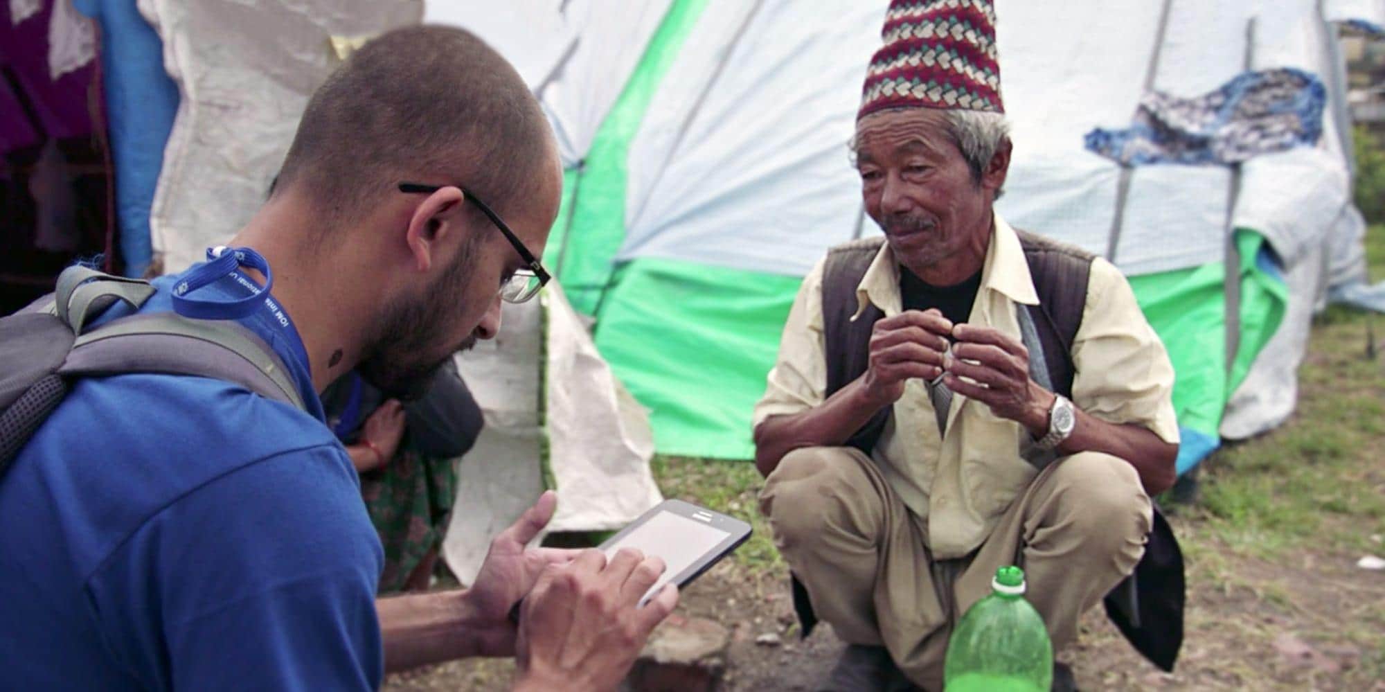 IOM Worker Speaking to Man By Shelters